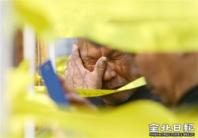 ▲ 눈물로 맞이하는 추모객   세월호가 1081일 만에 뭍으로 돌아온 지난해 3월 31일 전남 목포 신항에서 한 추모객이 노란 리본이 걸린 철책 앞에서 눈물을 훔치고 있다.(전북일보 박형민 기자)