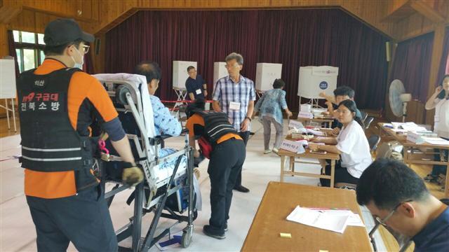 ▲ 익산시 웅포면 웅포초등학교에 설치된 투표소에 김모 씨(59)가 병상에 누운 채 투표를 위해 구급대의 도움을 받아 들어서고 있다.