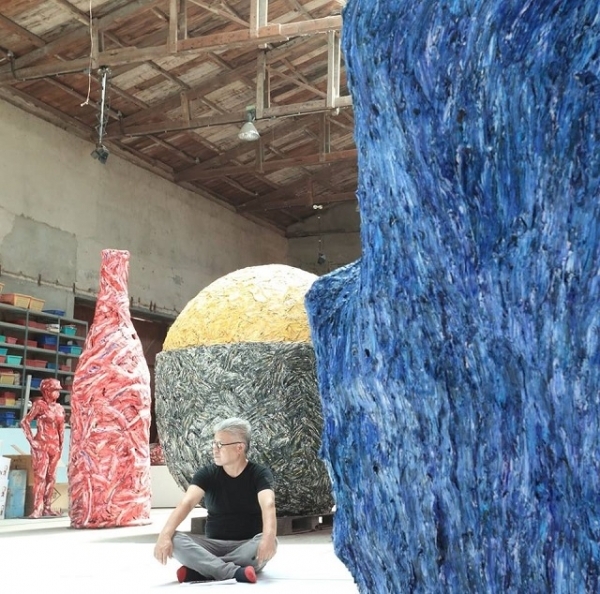 자신의 작품들 사이에 앉아있는 강용면 조각가.