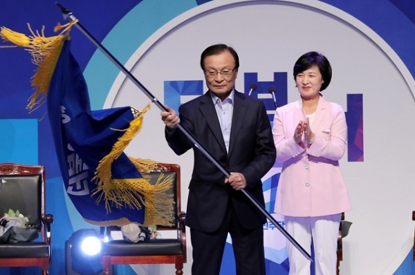 더불어민주당 이해찬 신임 대표가 25일 오후 서울 올림픽 체조경기장에서 열린 전국대의원대회에서 당기를 흔들고 있다. 오른쪽은 추미애 전 대표. 연합뉴스