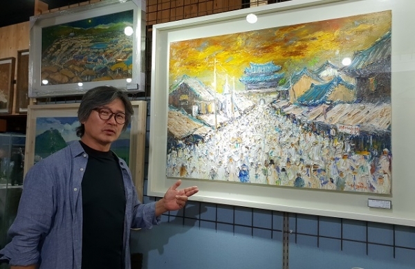 김정호 서양화가가 전주 오즈갤러리에서 신작 '평양 대동문거리'를 보며 작품 설명을 하고 있다.
