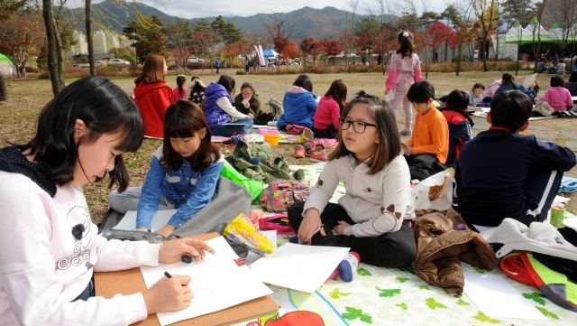 박수근 사생대회가 양구군 박수근 미술관일대에서 열려 대회에 참가한 학생과 학부모 교사들이 단풍이 물든 숲속에 모여앉아 그림을 그리고 있다.