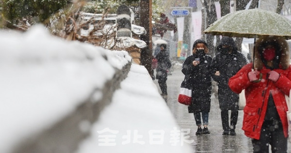전국적으로 눈과 비가 내린 11일 전주한옥마을을 찾은 관광객들이 눈 쌓인 돌담길을 따라 걷고 있다. 박형민 기자