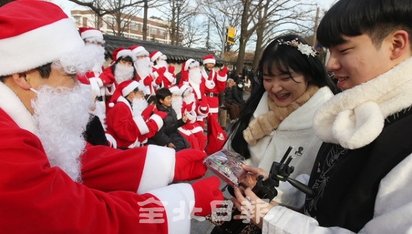 24일 전주 한옥마을에서 주민들과 상인들이 크리스마스이브를 맞이해 산타복장을 입고 관광객들을 대상으로 기념촬영과 선물을 나눠주고 있다. 조현욱 기자