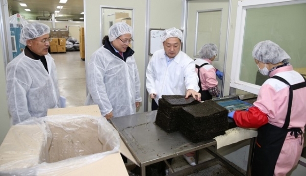 (유)동이식품 최일경 대표(오른쪽)가 공장을 방문한 정헌율 익산시장(왼쪽 두번째)에게 제품 생산과정을 소개하고 있다.