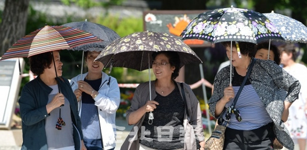 전주시의 낮 최고기온이 29도를 기록한 23일 뜨거운 햇빛을 피하기 우해 양산을 쓴 관광객들이 전주한옥마을 태조로를 걷고 있다. 기상청에 따르면 26일까지 30도가 넘는 불볕더위가 이어질 전망이다. 박형민 기자