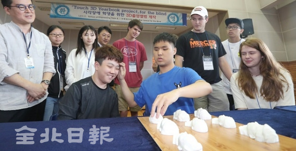 12일 전북맹아학교에서 시각장애인 학생이 미국 머서대학교 기술팀의 도움을 받아 만든 3D 촉각 졸업앨범과 친구의 얼굴을 만지며 비교하고 있다. 조현욱 기자
