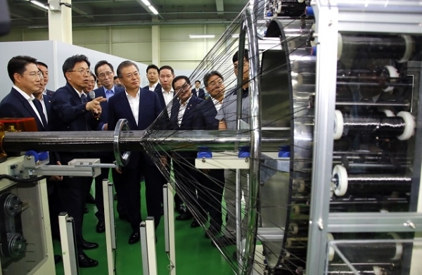 문재인 대통령이 20일 오후 전주시 효성첨단소재㈜ 전주공장에서 열린 탄소섬유 신규투자 협약식이 끝난 뒤 공장을 방문, 탄소섬유를 여러 모양의 지지대(원통, 사각 등)를 따라 감싸면서 직조해주는 장비 '브레이딩'을 살펴보고 있다. 연합뉴스