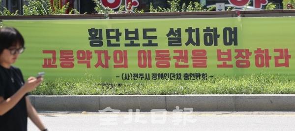 20일 전북대학교 구 정문 앞 기린대로에 교통약자 이동권 보장을 위한 횡단보도 설치를 요구하는 현수막이 걸려있다. 조현욱 기자