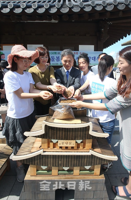 26일 전주 한옥마을 공영주차장 앞에서 열린 길고양이 급식소 돌보미 발대식에 참석한 김승수 전주시장과 돌보미들이 급식소에 첫 고양이 사료를 옮겨 담고 있다. 조현욱 기자