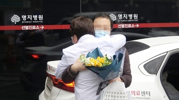 이왕준 이사장이 명지병원에서 입원 후 완치되어 퇴원한 17번 환자와 퇴원 직전 포옹을 하고 있다. 이 사진은 사태 초기, 코로나19의 성공적 치료를 상징적으로 보여준 장면으로 외신들이 주목한 장면이다. 사진제공= 명지병원.