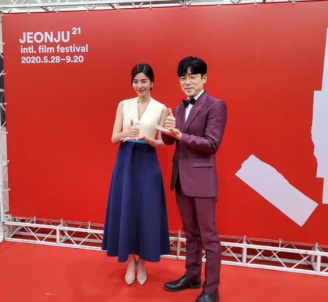 제21회 전주국제영화제 개막식 사회자로 나선 배우 김규리와 이승준이 본 행사에 앞서 코로나19 극복을 위해 애쓰는 의료진을 응원하는 뜻을 담은 '덕분에 챌린지' 동작을 취하고 있다.