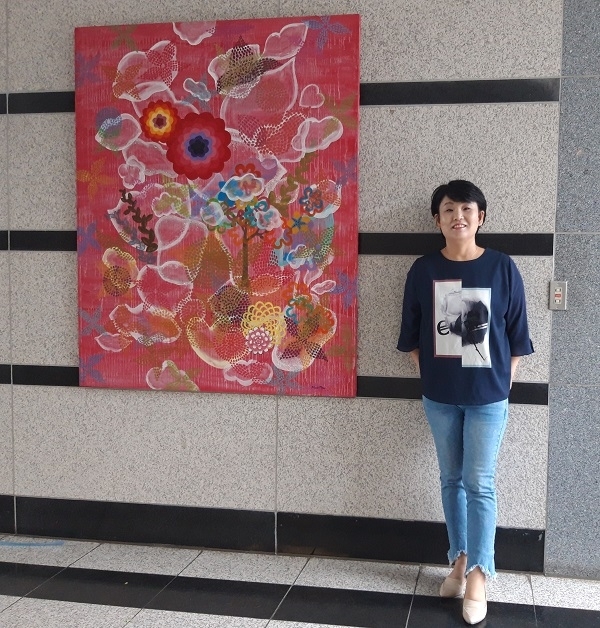 정미정 작가가 본인의 전시 작품 옆에서 포즈를 취하고 있다.