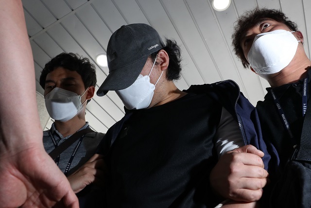 창녕 아동학대 계부(모자 착용)가 15일 오전 영장실질심사(구속 전 피의자 심문)를 받기 위해 창원지방법원 밀양지원으로 이동하며 취재진 질문에 답하고 있다. 이 계부는 자신의 의붓딸을 쇠사슬 등으로 학대한 혐의를 받는다. 연합뉴스