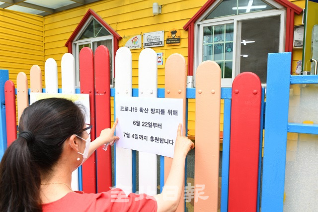 익산시가 코로나19의 외부 유입과 확산방지를 위해 '고강도 생활속 거리두기'로 전환하며 2주간 공공시설 휴관과 어린이집 휴원 등에 들어가 23일 익산 즐거운꽃동산어린이집에서 원장이 7월 4일까지 휴원을 알리는 공고문을 붙이고 있다. 오세림 기자