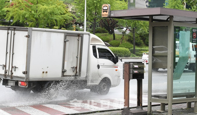 비만 오면 도심 인도와 차로변에 생기는 물웅덩이로 보행자들이 불편을 겪고 있는 가운데 20일 버스정류장 앞에 생긴 물웅덩이로 인해 차량들이 물보라를 일으키고 있다. 오세림 기자