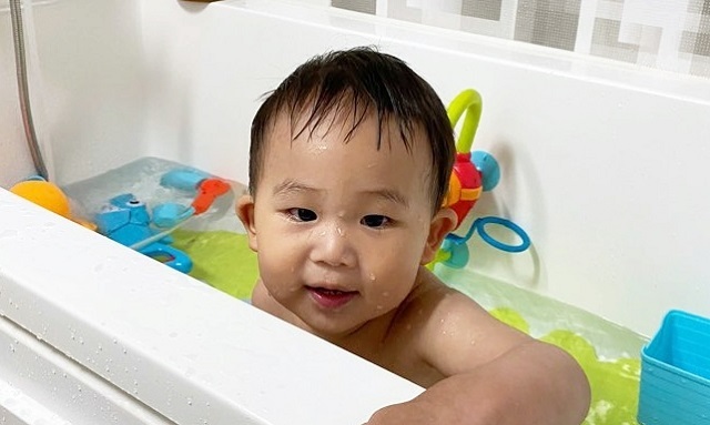 여름휴가를 포기한 부모 결정에 욕조에서 물놀이를 즐기는 아이.