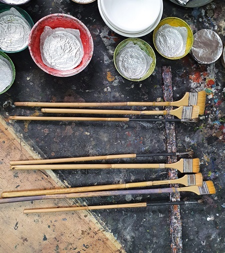 큰 붓을 휘적이며 그리는 데 맞는 작업 도구가 눈길을 끈다.