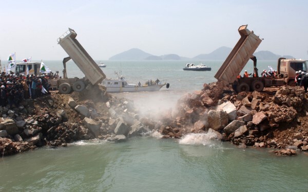 2006년 4월 21일 낮 12시 46분 새만금의 마지막 끝물막이 작업이 이루어지고 있는 현장. 물길을 완전히 차단하는 순간이다. 바지선의 물망태 투하가 끝나자 트럭들이 쉴새없이 돌을 쏟아부으며 마지막 물길을 막고 있다.