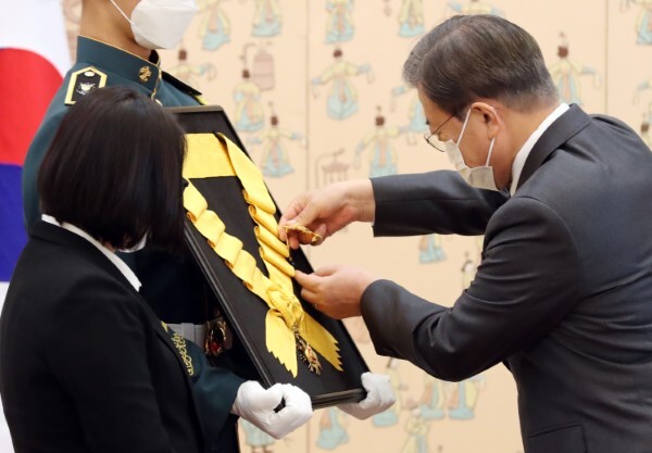 문재인 대통령이 12일 오전 청와대에서 열린 고(故) 전태일 열사 훈장 추서식에서 둘째 동생 전순옥 씨 옆의 의장병이 들고 있는 국민훈장 무궁화장 추서판에 부장을 걸어주고 있다. /사진=연합뉴스