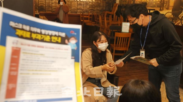 마스크착용 의무화가 본격적으로 실시된 13일 전주의 한 카페에서 공무원들이 마스크 착용 안내문을 나눠주며 단속 시작을 알리고 있다. /조현욱 기자