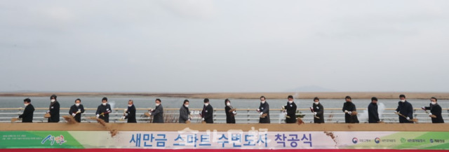 18일 군산시 새만금방조제 소라쉼터에서 열린 새만금 스마트 수변도시 착공식에서 김현미 국토부 장관과 송하진 도지사, 소순열 새만금위원회 민간위원장 등 참석자들이 첫 착공을 축하하는 시삽을 하고 있다. /조현욱 기자