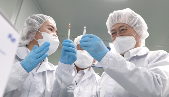 문재인 대통령은 18일 코로나19 백신접종용 최소잔여형(LSD) 백신주사기 생산 업체인 군산의 (주)풍림파마텍을 방문해 생산라인을 줄러보고 LSD 백신주사기를 살펴보고 있다. /오세림 기자