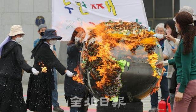 22일 지구의 날을 맞아 전주시청 광장에서 전북시민단체가 기후위기 비상행동 기자회견을 열고 지구 태우기 퍼포먼스를 하고 있다. /조현욱 기자