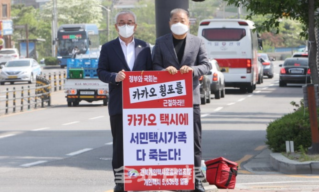 29일 박상익 전북개인택시조합 이사장(왼쪽)과 조합원이 김성주 더불어민주당 전북도당 위원장 지역사무실 앞에서 카카오모빌리티의 택시 플랫폼 업계 독점과 불공정 행태에 대한 규탄 피켓시위를 하고 있다. /조현욱 기자