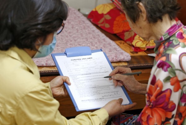 지난해 정부 재난지원금 지급 당시 도내 한 공무원이 지역 어르신의 신청서 작성을 돕고 있다. /전북일보 자료사진