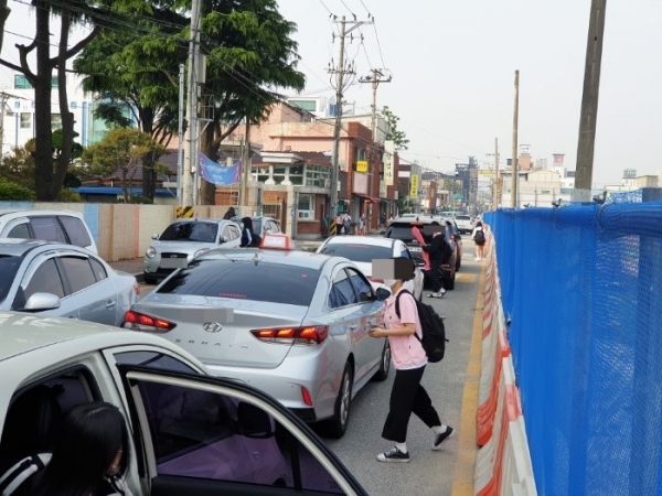 14일 오전 8시 5분께 익산 이일여자중고등학교 정문 앞 평동로7길. 인접 공사 현장의 펜스가 도로 쪽으로 이전 설치돼 2m 가량 공간이 사라지면서 등하굣길 심각한 교통체증이 빚어졌고 학생들은 사고 위험에 노출됐다.