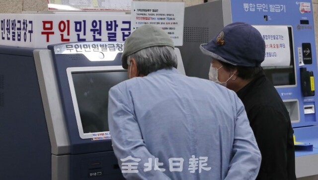 26일 전주시청 민원실에서 무인민원발급기를 이용하는 어르신이 어려움을 겪자 자원봉사자가 사용 방법을 알려주고 있다. /조현욱 기자