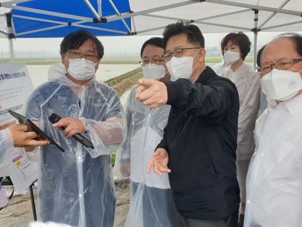 김현수 농림축산식품부 장관이 논두렁 한복판에 설치돼 있는 스마트영상물꼬제어기를 가리키며 농촌진흥청 서명철 연구관에게 질문을 하고 있다.