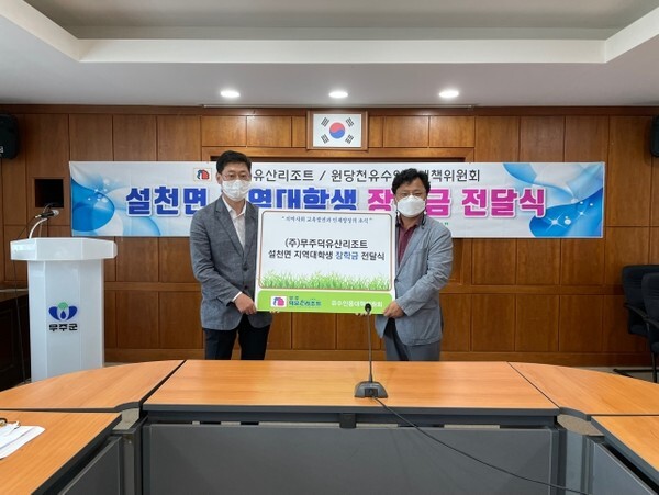 부영그룹 무주덕유산리조트 김병철 대표가 원당천유수인용대책위원회 김종국 위원장에게 장학증서를 전달하고 있다.