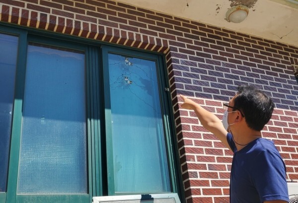 문서운 씨의 사위 장현규 씨가 산탄총으로 인해 창문에 생긴 구멍을 가리키고 있다