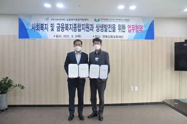 2일 유용우 전북신용보증재단 이사장(좌), 이원식 전북사회복지사협회장이 업무협약을 맺고 기념촬영을 하고 있다.