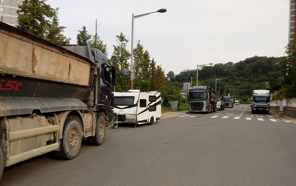 아파트 주변 이면도로에 대형 화물차량이 주차되어있는 모습