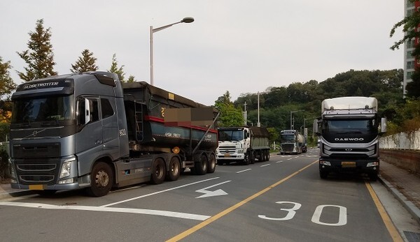 아파트 주변 이면도로에 대형 화물차량이 주차되어있는 모습