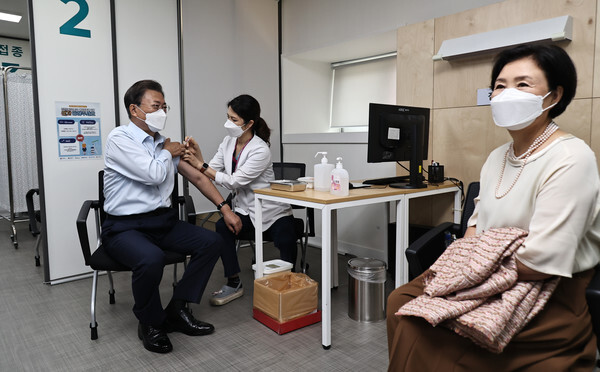 문재인 대통령이 15일 서울 국립중앙의료원 코로나19 중앙예방접종센터에서 코로나19 백신 추가 접종을 받고 있다. 김정숙 여사(오른쪽)가 차례를 기다리고 있다. /연합뉴스