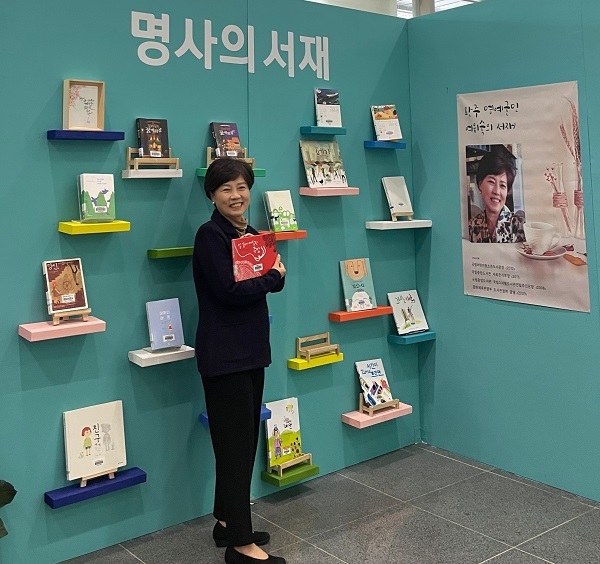 여위숙 전 관장이 자신의 저서가 소개된 완주군청 로비 '명사의 서재'에서 책을 들어보이고 있다.