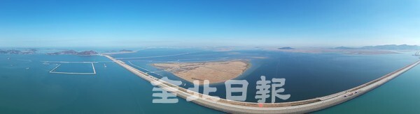 1991년 11월 28일 시작된 새만금 간척 종합개발 공사가 30년을 맞았다. 왼편으로 섬이었던 고군산 일대는 이제는 연육교로 자동차를 타고 갈 수 있게 됐다. 그 앞으로 새만금 신항만 공사가 한창이다.김제 진봉면을 잇는 동서 도로가 개통했고 신항만 배후부지가 형성되어가고 있다. 오른편으로는 동진강 하구 및 개화도 일대와 2023년 새만금 세계잼버리 부지가 땅으로 변해 새만금의 모습이 점점 드러나고 있다. 새만금 사업 30년간의 우여곡절을 보여주듯 카메라 렌즈의 왜곡으로 새만금 방조제 도로가 휘어 보이며 군산과 부안을 잇고 있다. /사진 = 오세림 기자