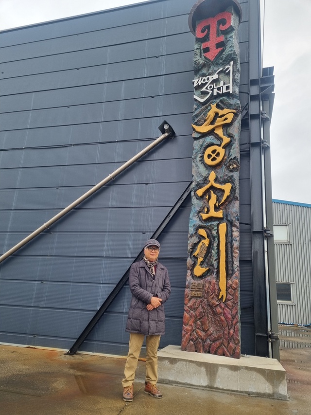  군산의 목재회사에 기념조형물로 들어선 소나무 서각 예술작품과 전승택 작가(사진=문정곤 기자)